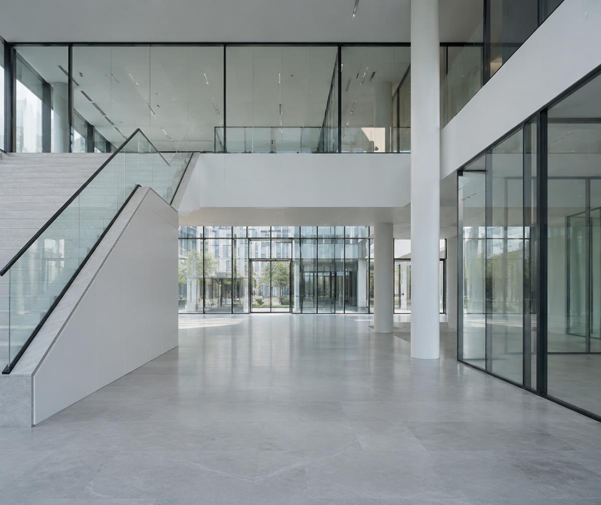 Spotless modern commercial building lobby with glass partitions and pale stone floors